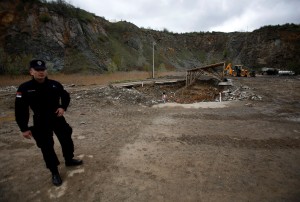 A Serbian police officer guards a mass grave site in the village of Rudnica, 280 kilometers (170 miles) south of Belgrade, Serbia, Thursday, April 17, 2014. The mass grave is believed to contain at least 250 bodies of Albanian victims killed during the Kosovo war. (AP Photo/Darko Vojinovic)