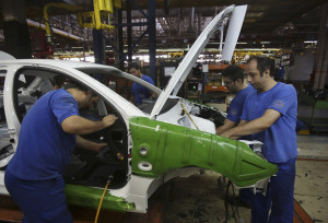 Iranian car workers assemble a car at the state-run Iran-Khodro automobile manufacturing plant near Tehran, Iran, Sunday, June 29, 2014. Iran began exporting automobiles to Russia for the first time in five years on Sunday, after meeting upgraded emission standards, the country's largest auto manufacturer said. (AP Photo/Vahid Salemi)