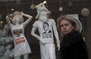 A woman walks past a shop window with a T-shirt on display reading, 'I Believe in the Ruble', in downtown Moscow, Russia, on Monday, Dec. 22, 2014. The ruble has been the worst performing currency this year along with the Ukrainian hryvnia, having lost half of its value. Its collapse in the past weeks sparked a consumer boom as worried Russians flocked to the shops to buy cars and durable goods before prices rose further. (AP Photo/Pavel Golovkin)