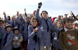 Syrian refugee students wave to welcome United Nations Secretary-General Ban Ki-moon, unseen, to Zaatari Syrian refugee camp, in Mafraq, Jordan, near the Syrian border, Saturday, Dec. 7, 2012. U.N. Secretary-General Ban Ki-Moon on Friday called on the Syrian government to "stop the violence in the name of humanity", during a visit to the Zaatari refugee camp in Jordan, close to the Syrian border. (AP Photo/Mohammad Hannon)